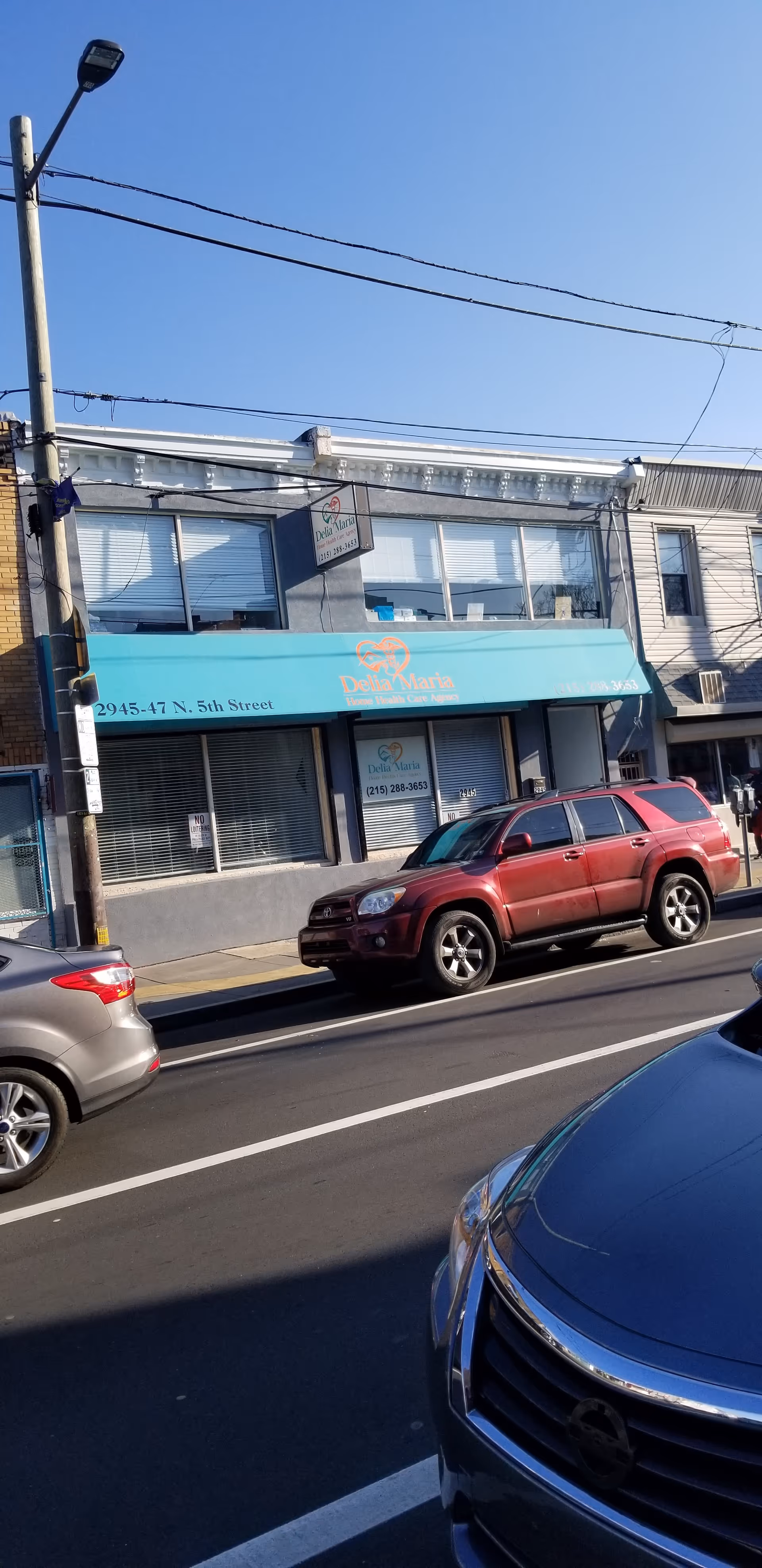 Exterior storefront of Delia Maria Home Care Agency with teal awning on a city street.