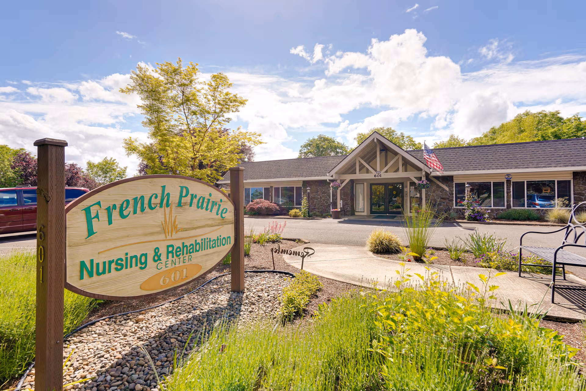 Front view of French Prairie Nursing & Rehabilitation Center with sign and landscaped entrance