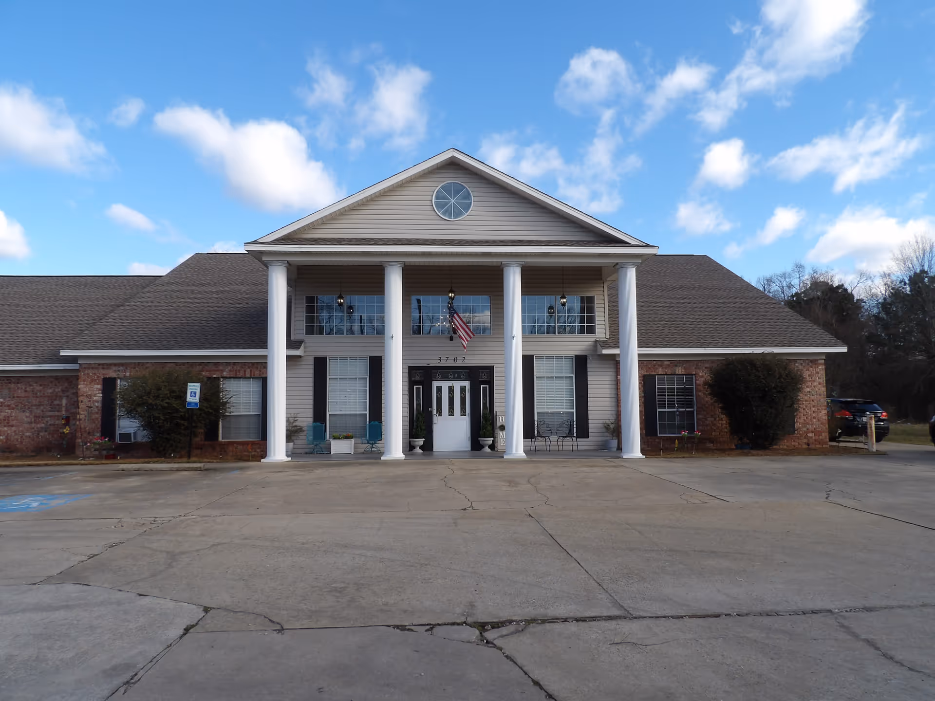 Front exterior of a large senior living facility with white columns and a peaked roof.
