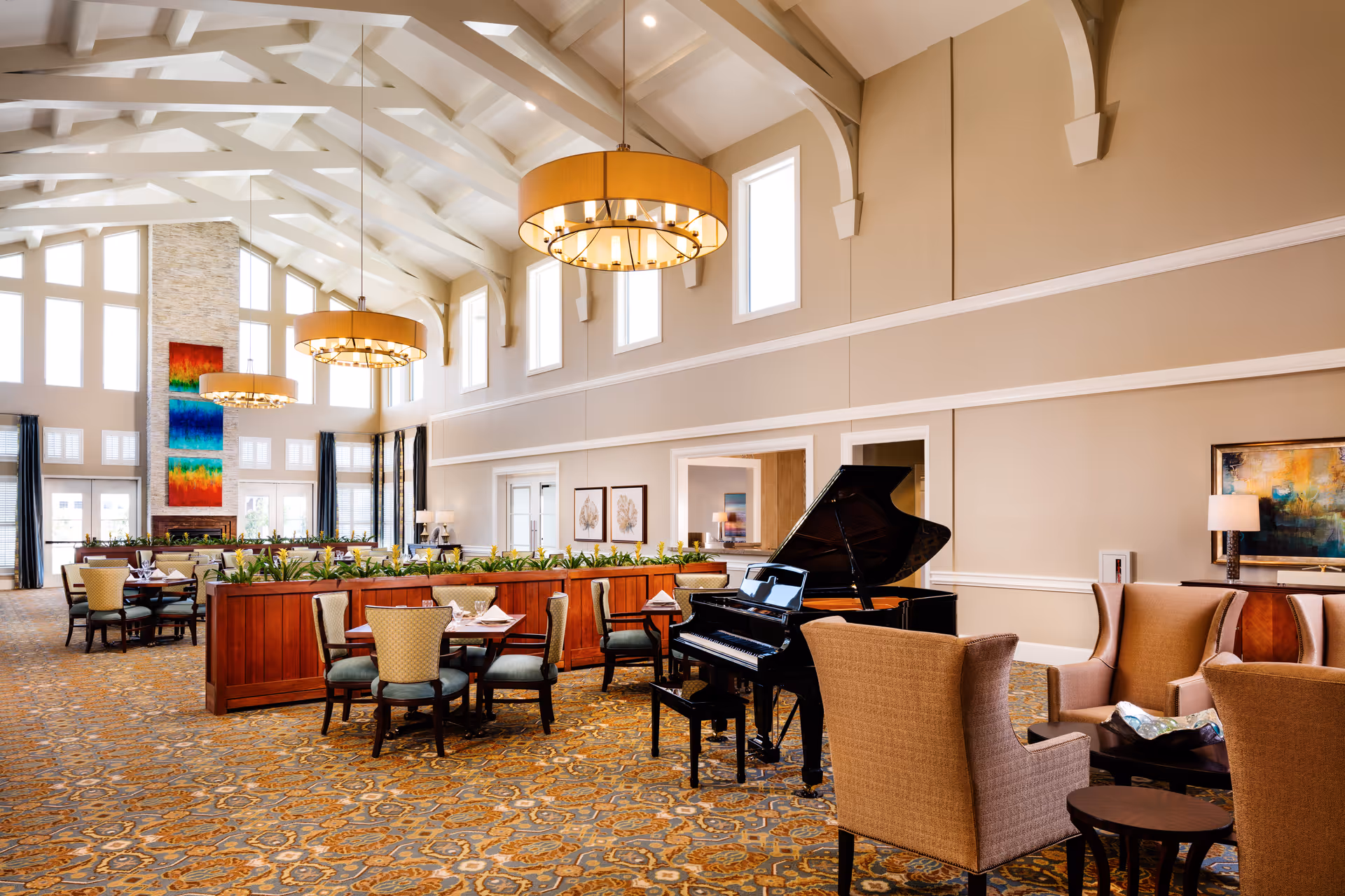 Spacious senior living lounge with a grand piano, seating areas, and vaulted ceilings.