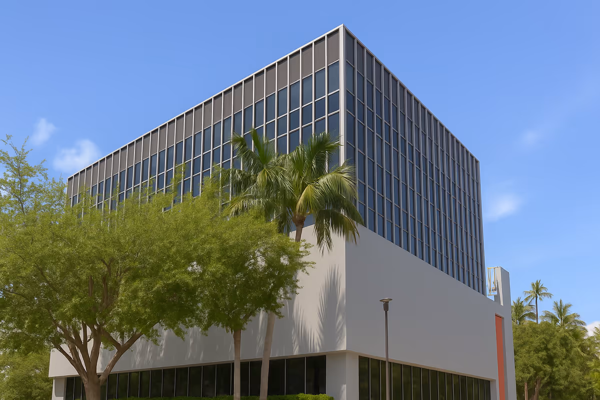 Modern multi-story building with glass windows, palm trees, and a blue sky.