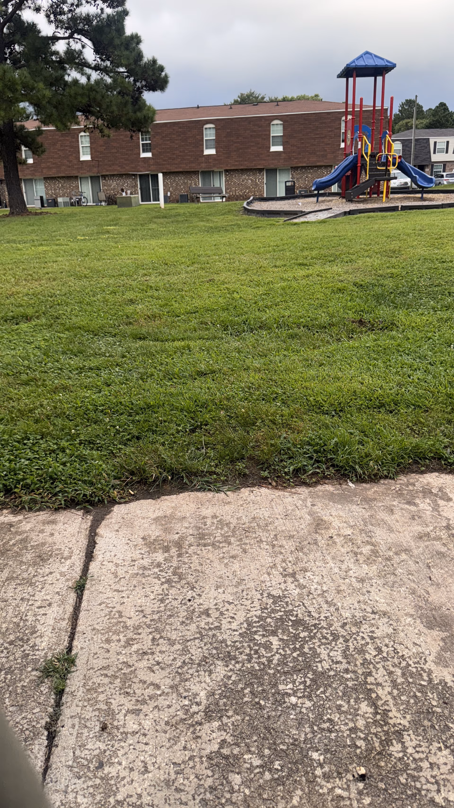 Brick senior facility with a grassy yard and a blue playground in the distance.