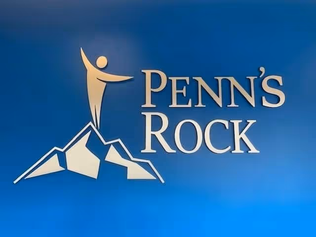 Blue wall with a mountain logo and 'Penn's Rock' lettering.