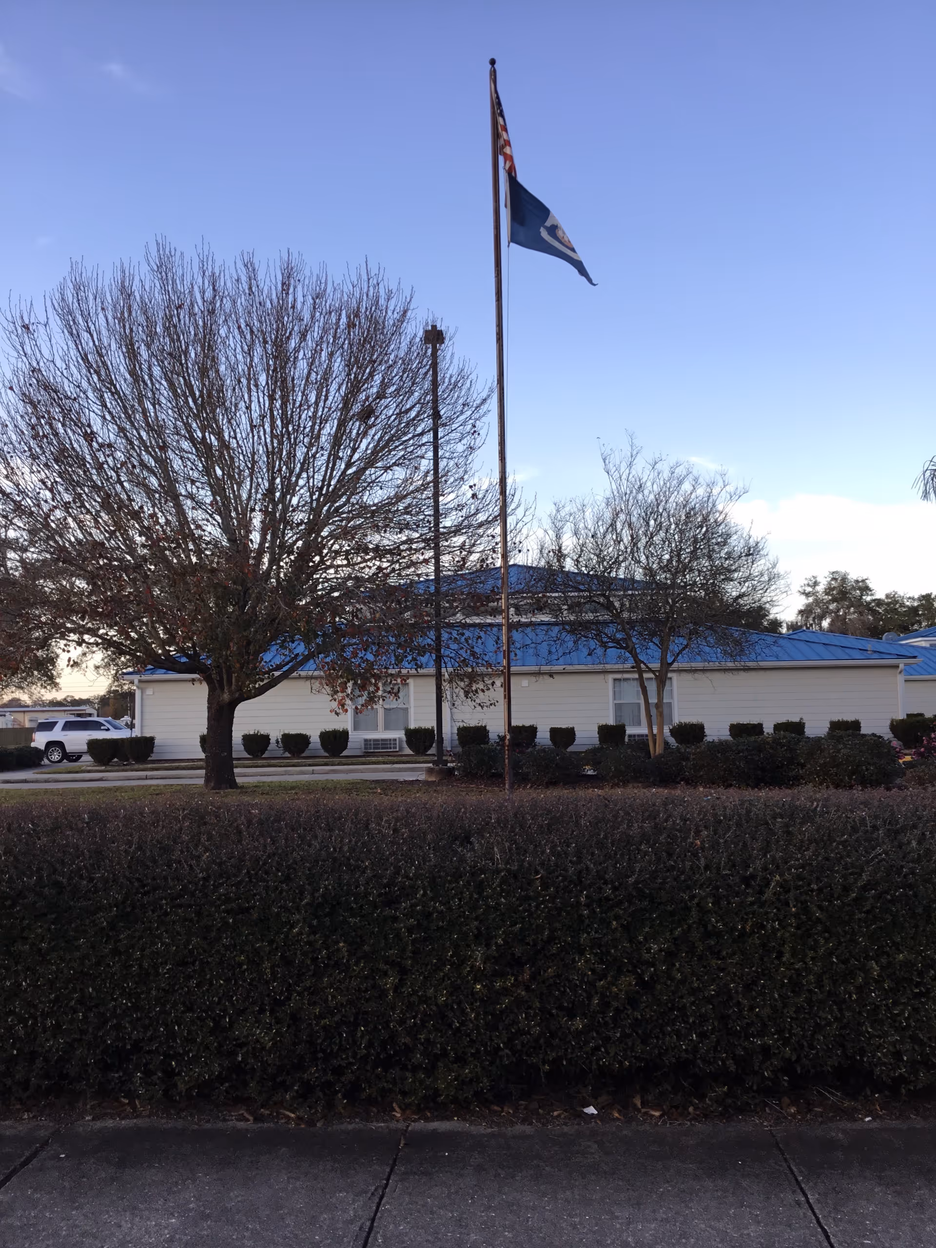 Exterior view of Riverbend Nursing and Rehabilitation Center with flagpoles and trees.