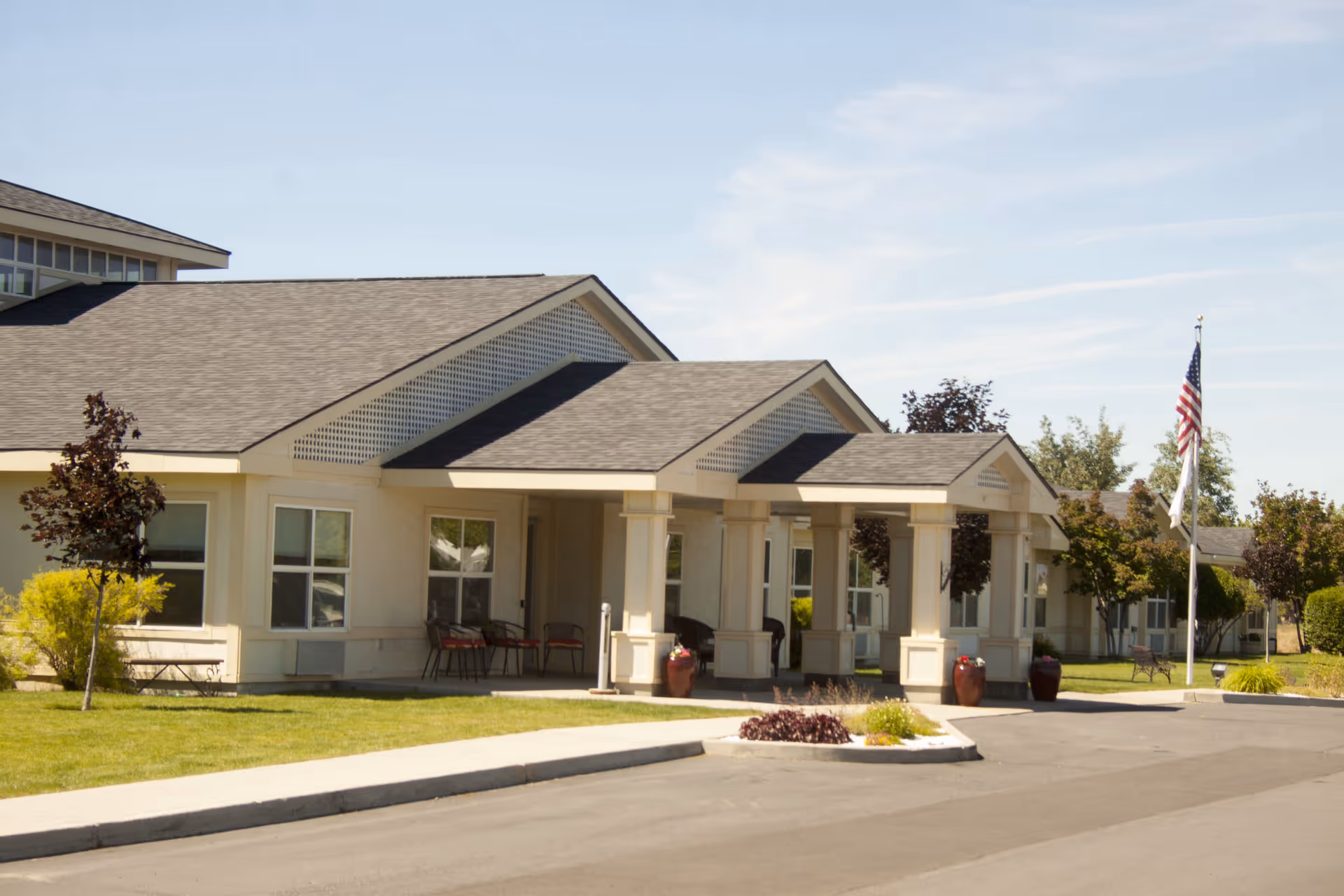 Front view of Settler's Park Senior Living entrance with portico and American flag.