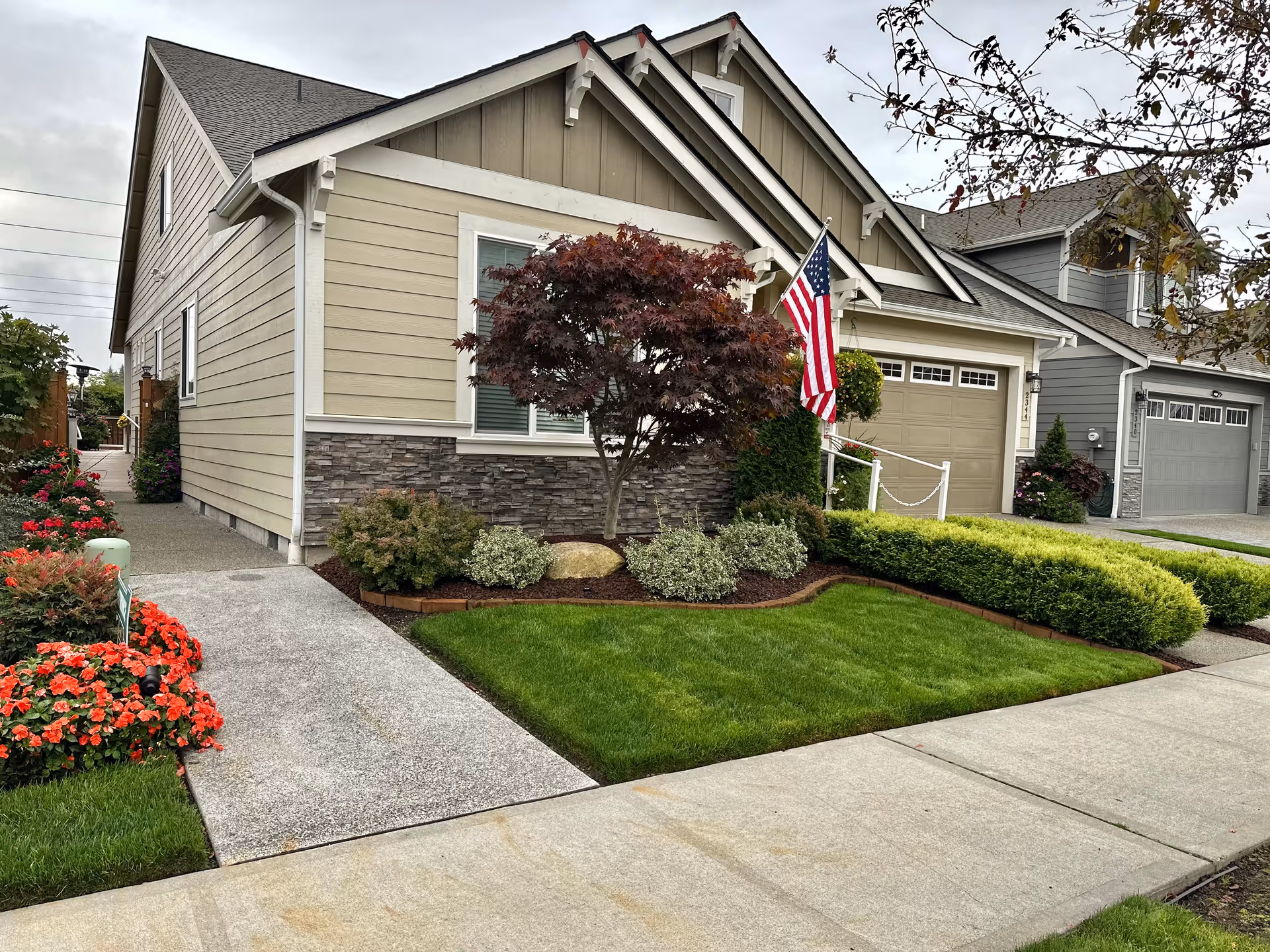 Front view of a neat single-family home with landscaped yard and an American flag.