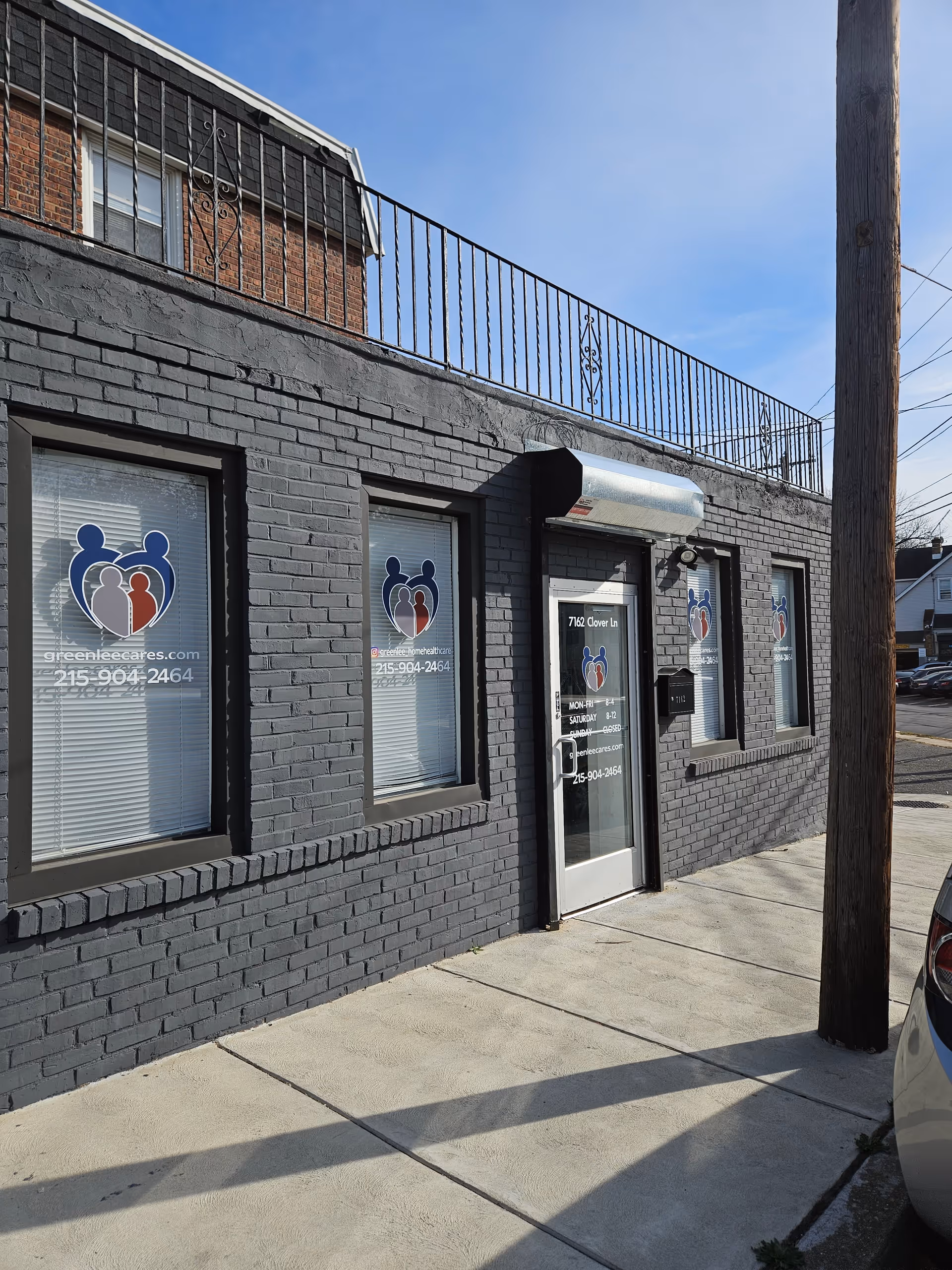 Exterior of GreenLee Home Care building with gray brick, windows bearing logos, and a glass door.