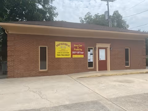 Exterior brick building with yellow banners near a red entrance door.