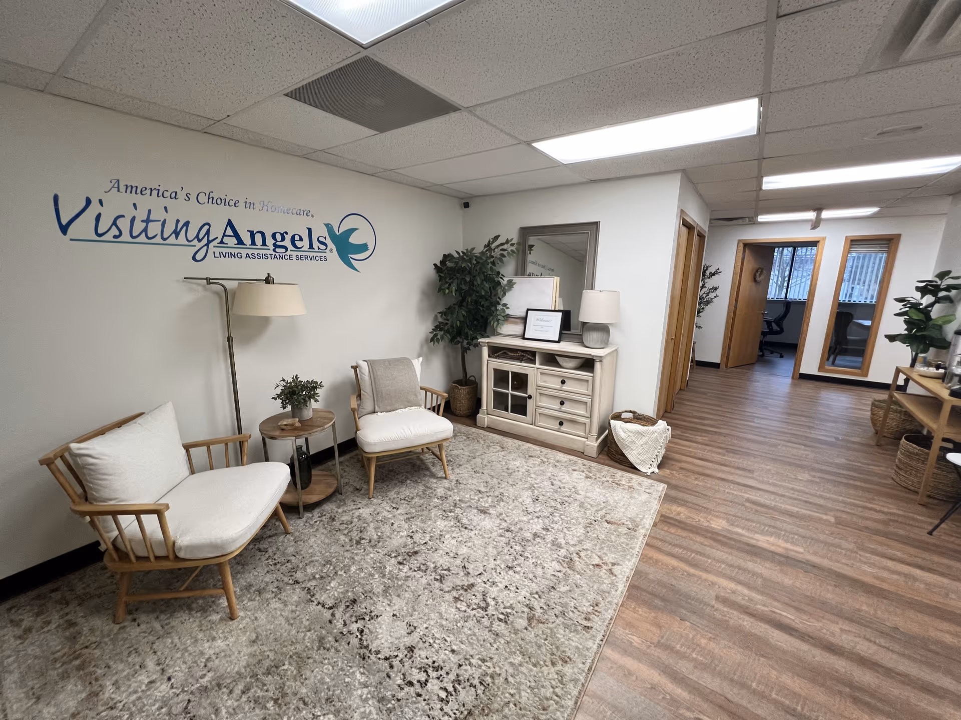 Reception/lounge area of Visiting Angels Senior Home Care with seating, plants, and logo wall