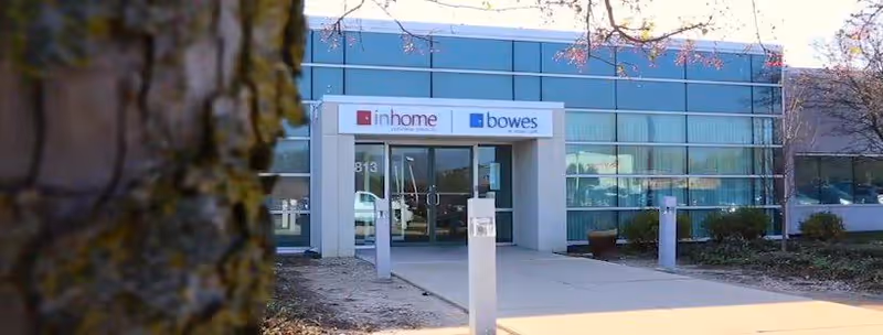 The glass-front entrance of a senior living facility features signage above the doors.