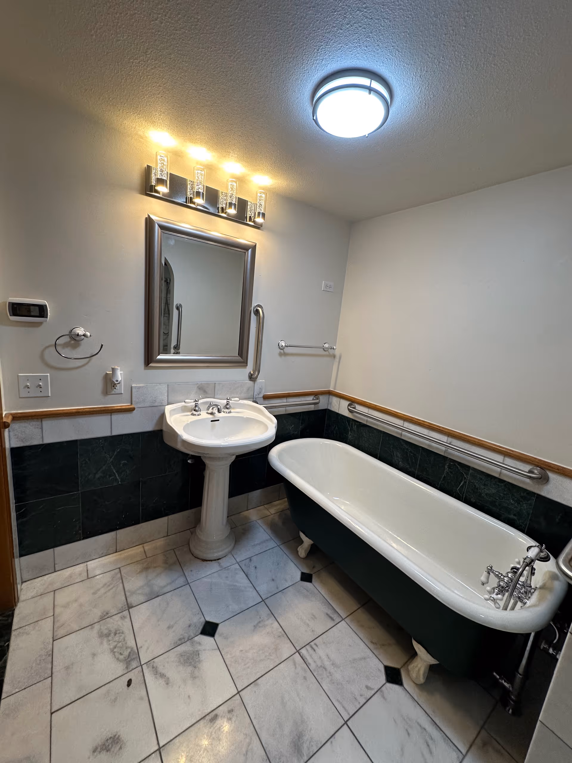 Small bathroom featuring pedestal sink, mirror, overhead light, and a clawfoot bathtub.