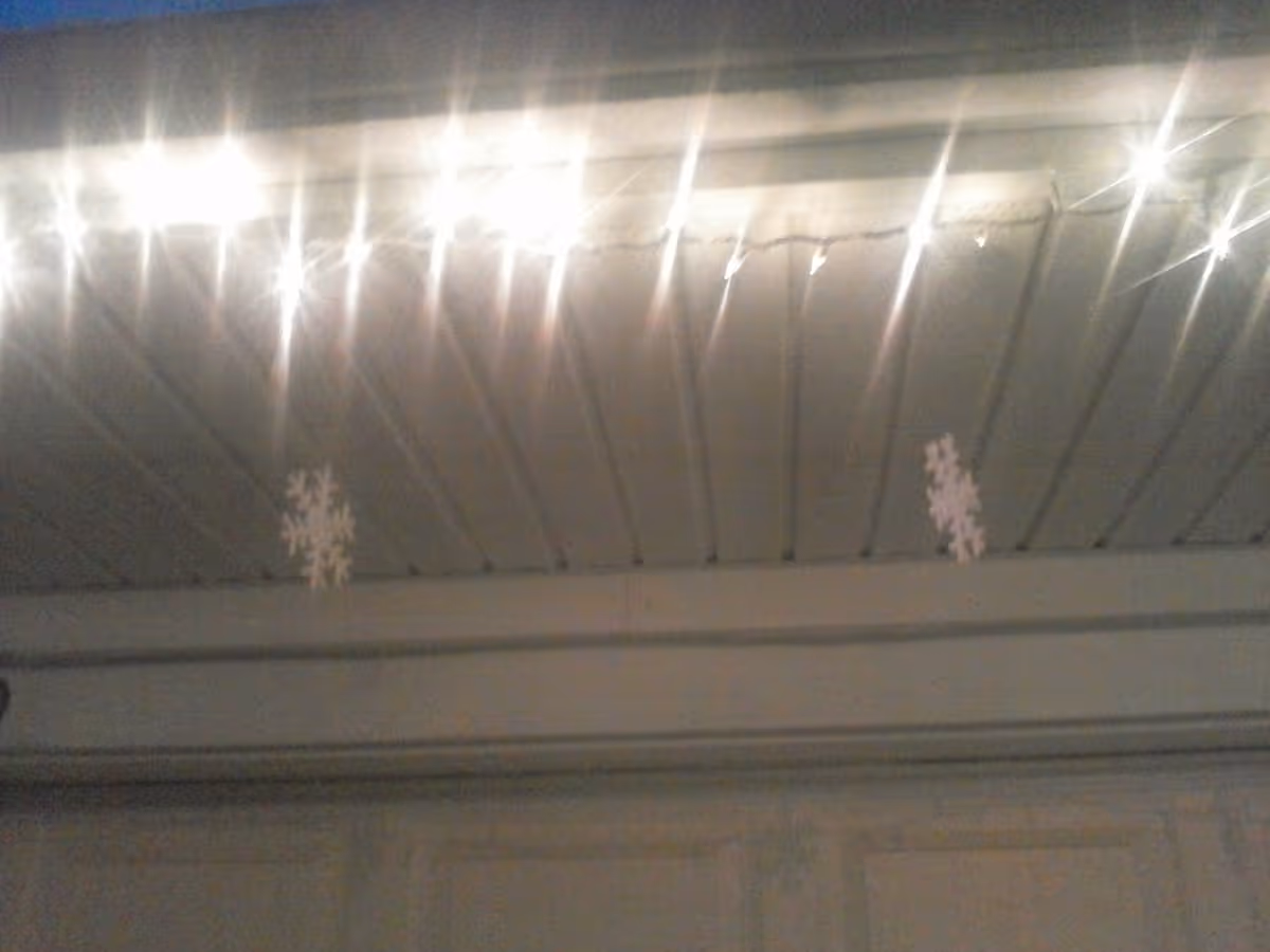 Indoor ceiling with bright lights and hanging snowflake decorations.