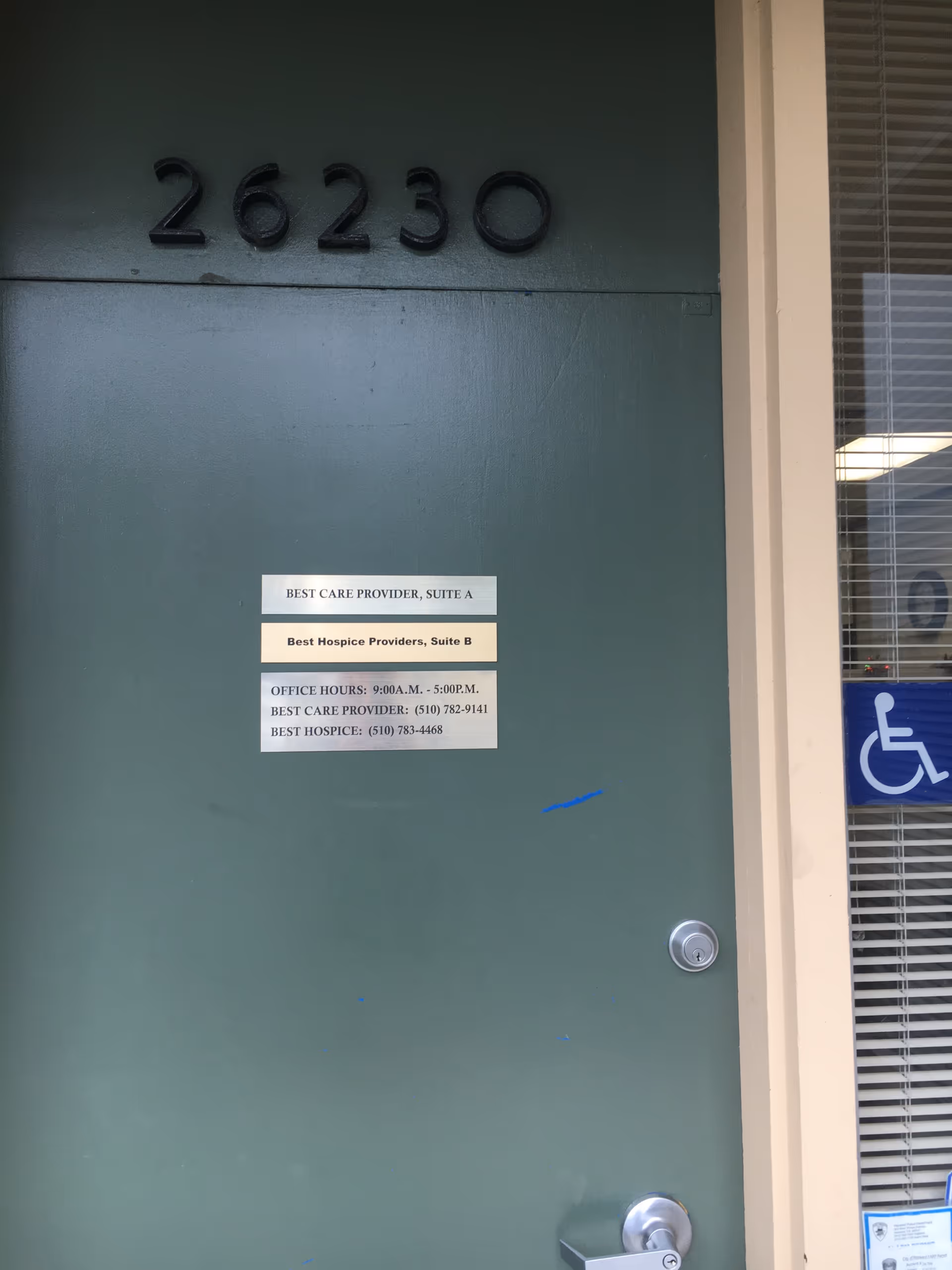Green entry door with suite signs and a wheelchair-accessible window.