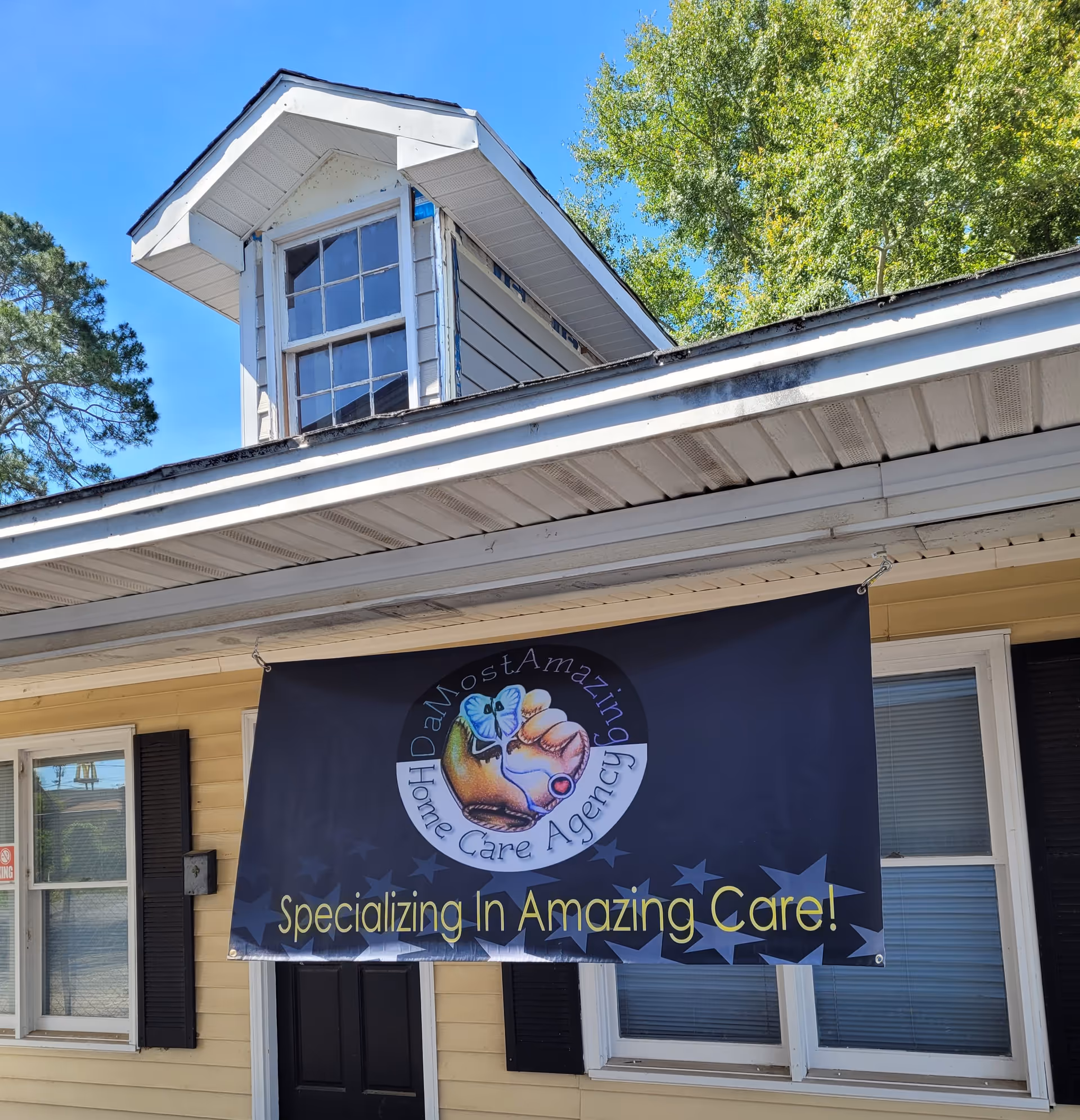 Exterior of a yellow building with a DaMostAmazing Home Care Agency banner.