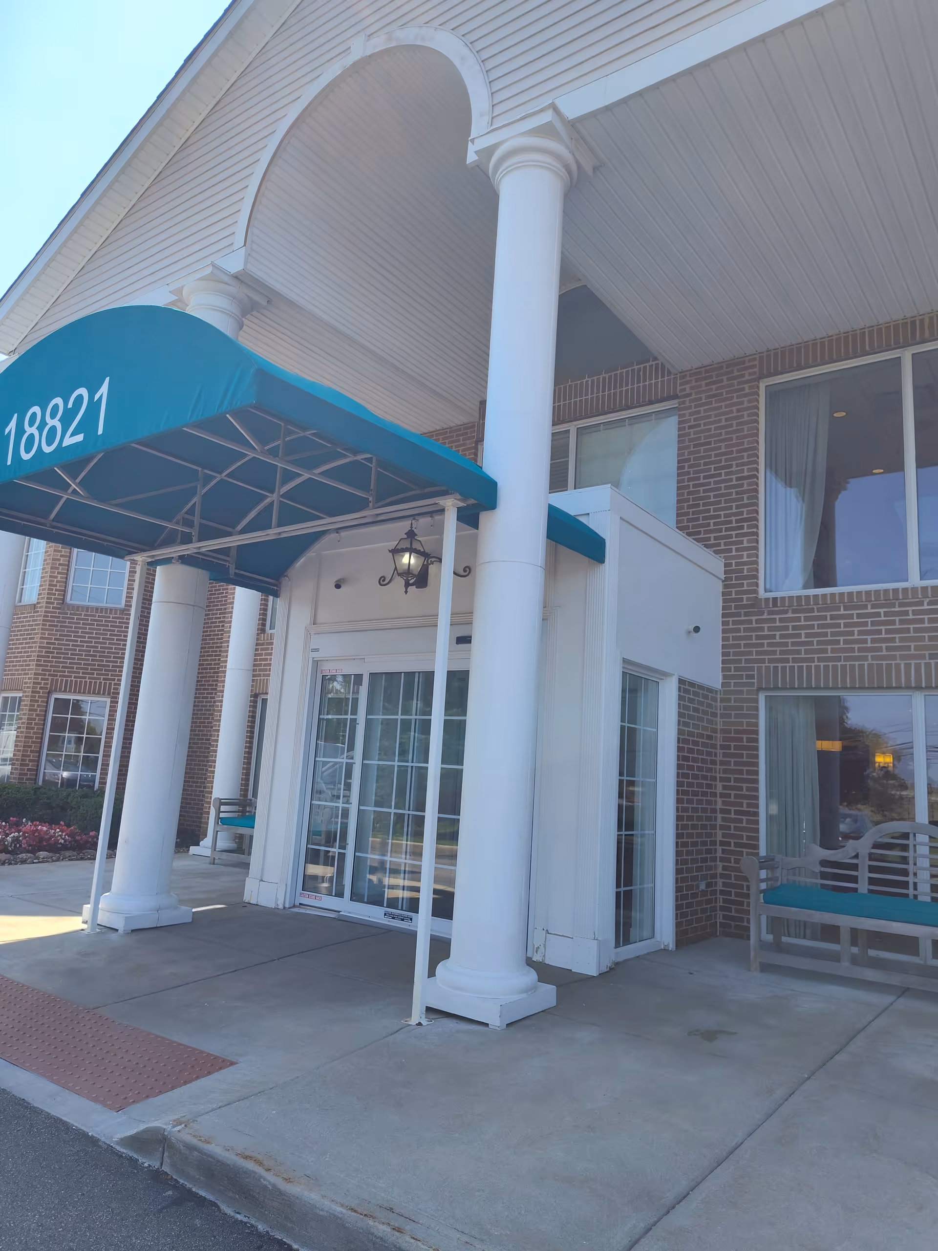 Exterior entrance of Shurmer Place at Altenheim with white columns and teal awning.