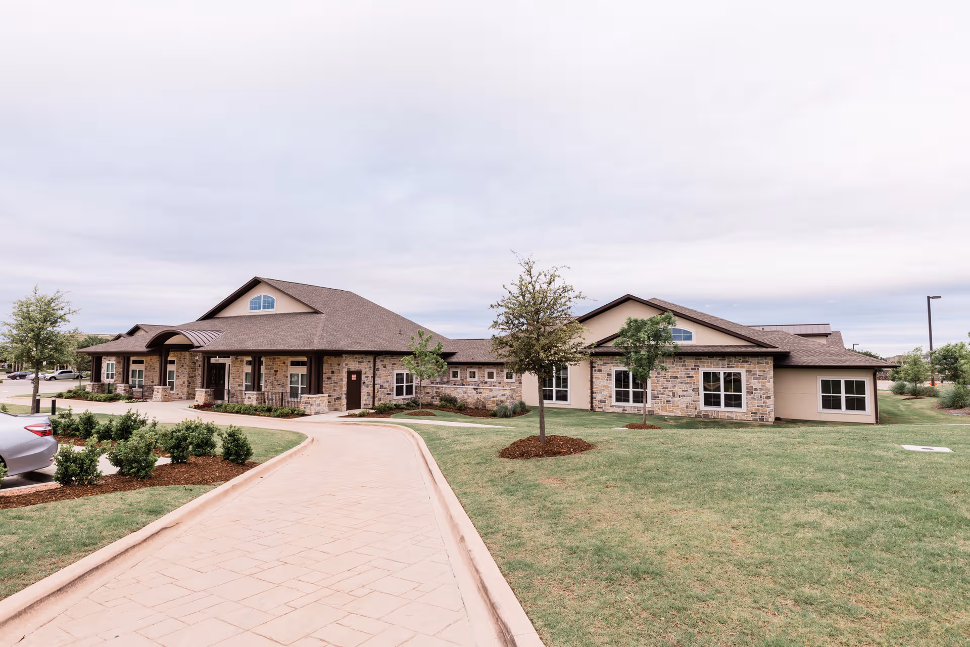 Exterior view of a single-story stone-and-brick senior living facility with a curved walkway