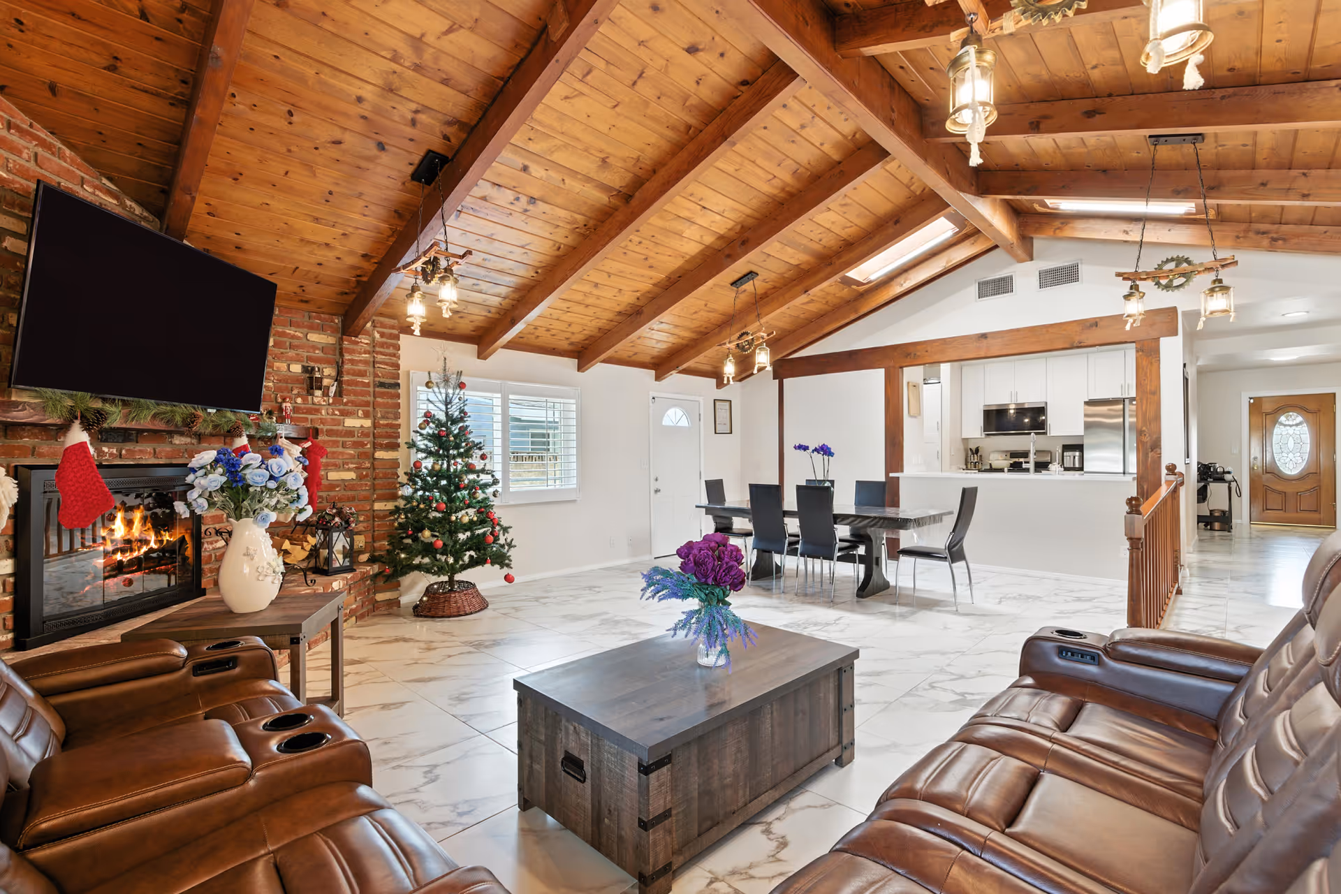 Open living room with fireplace, Christmas tree, leather seating, and adjacent dining area.