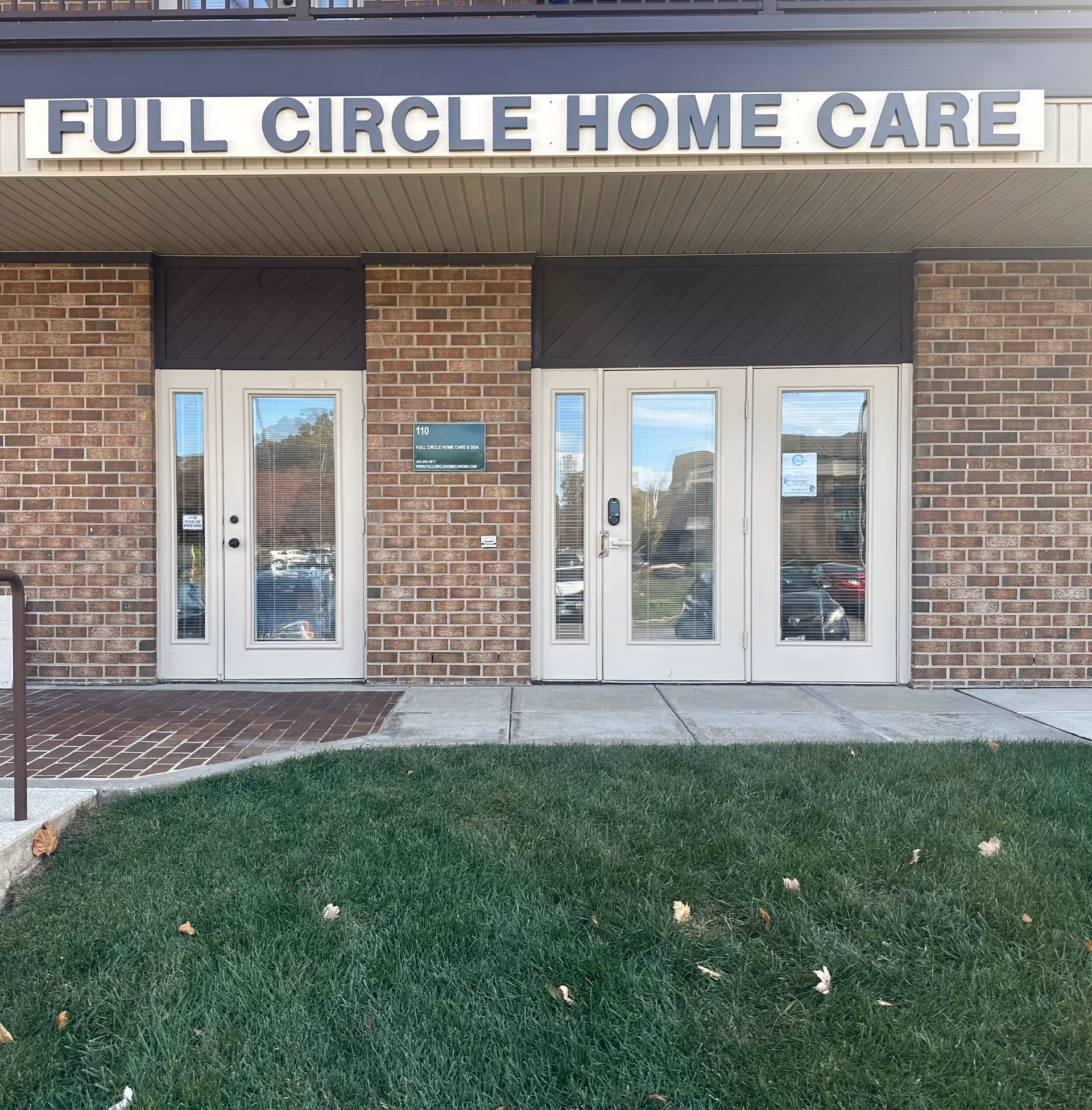 Brick building entrance with double glass doors and Full Circle Home Care sign.