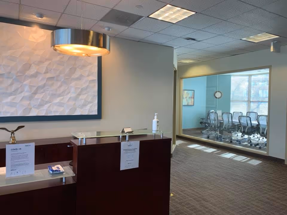 Modern reception area with curved desk, textured wall art, and glass-walled conference room.