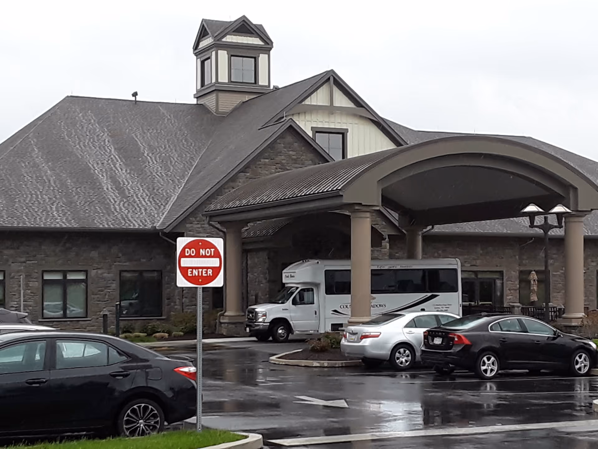 Front view of a Country Meadows retirement community entrance with a bus.