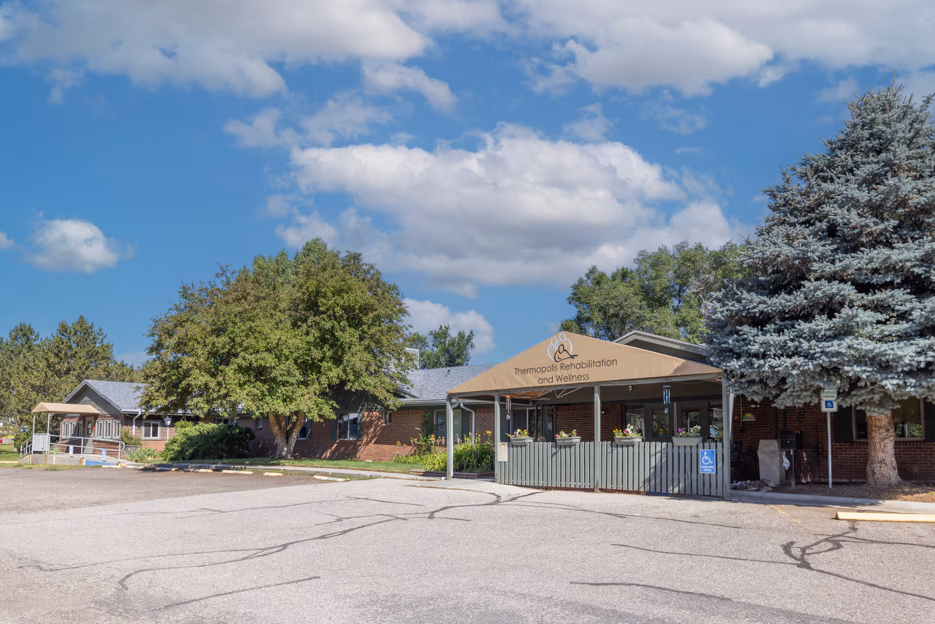 Exterior view of Thermopolis Rehabilitation and Wellness facility with entrance canopy and parking.