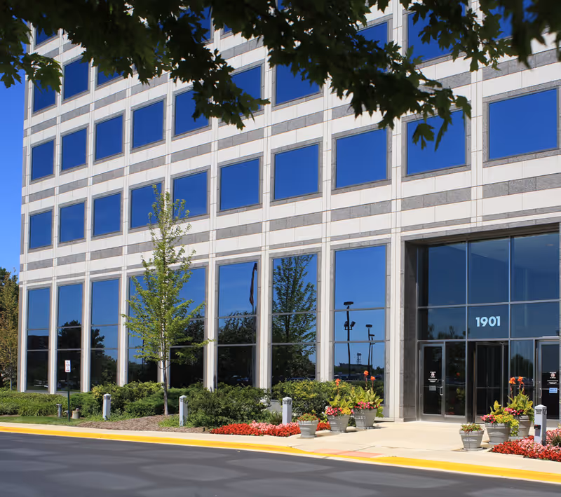 Exterior of Home Health Providers, PC building with glass facade, blue windows, and planters.