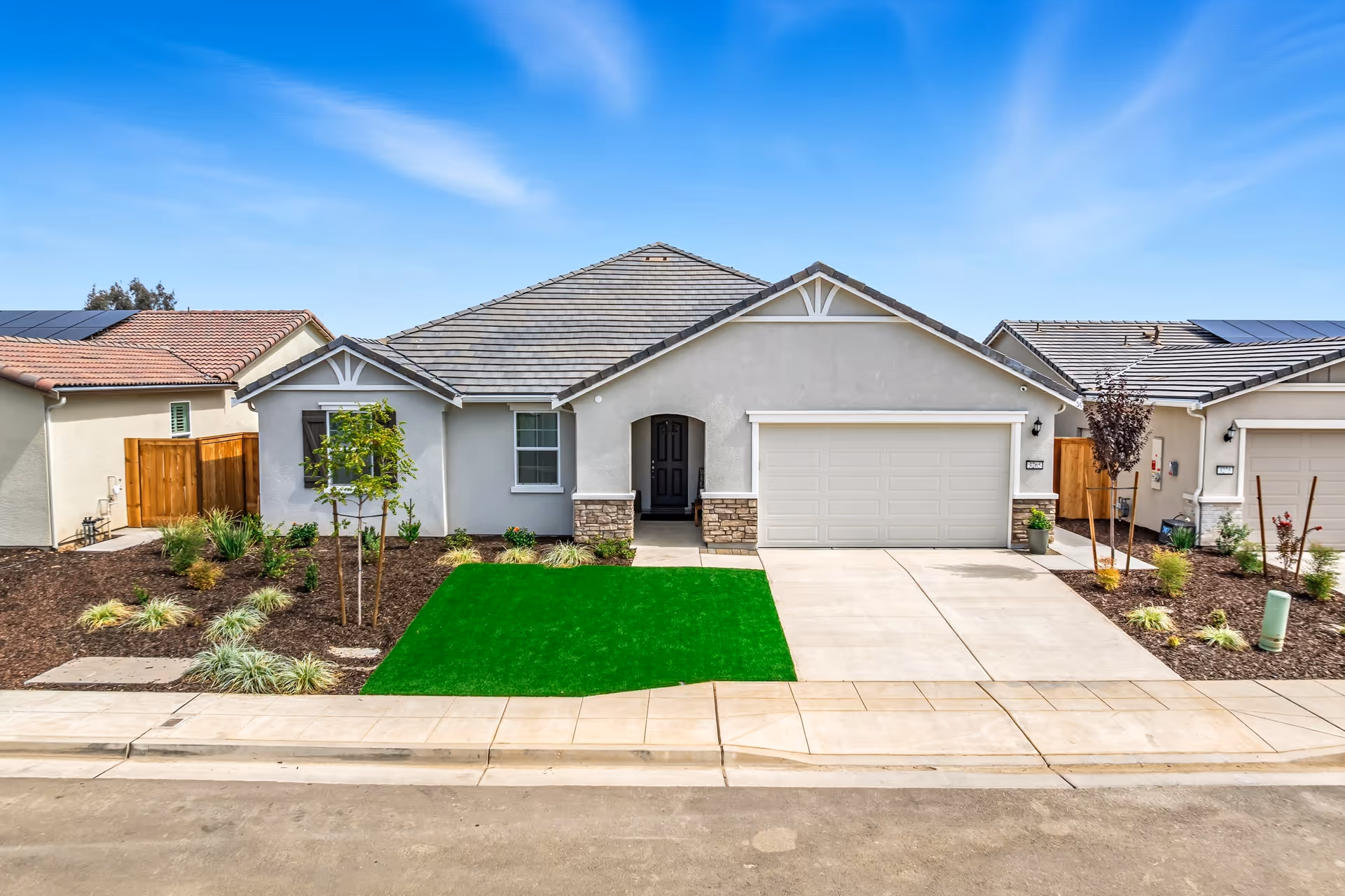 Single-story care home exterior with a two-car garage and neatly landscaped front yard.