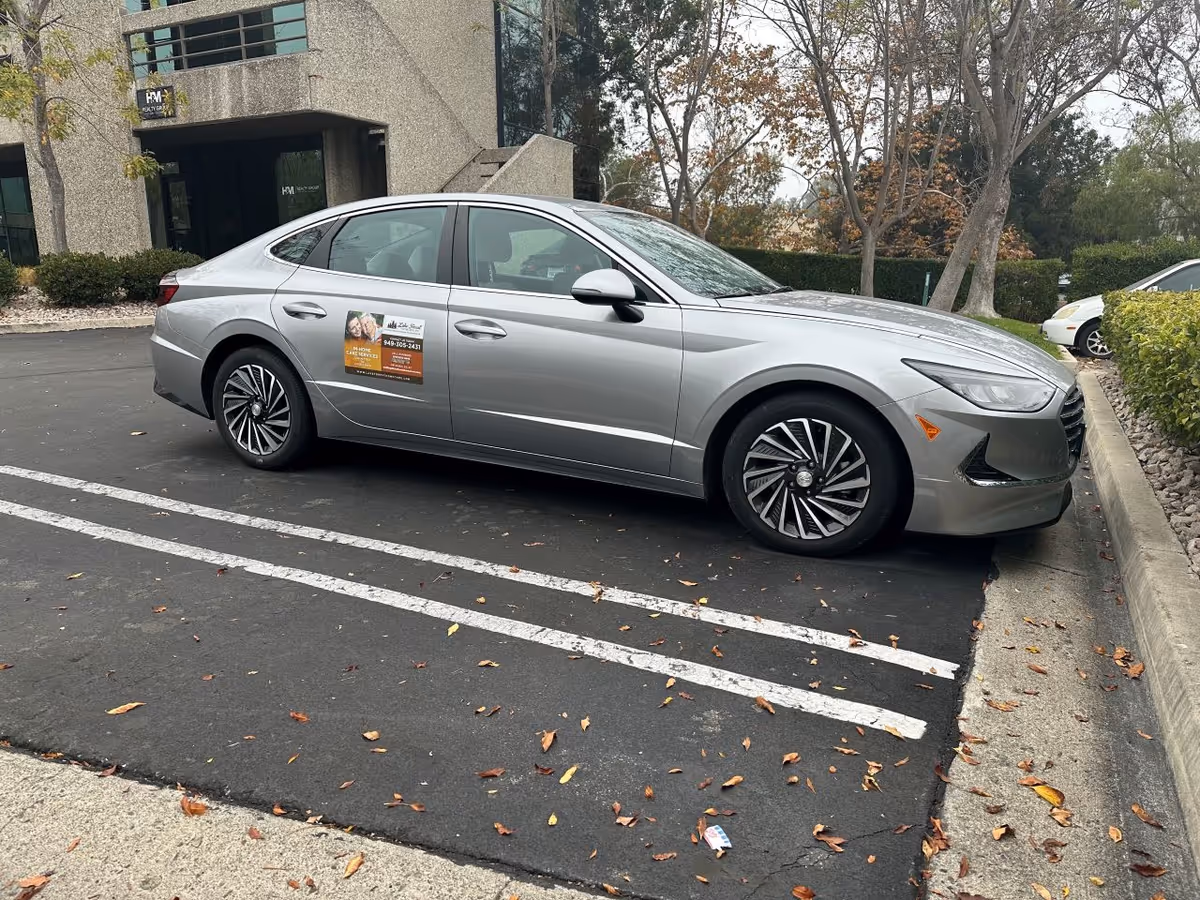 Silver sedan parked in a lot in front of a modern building exterior.