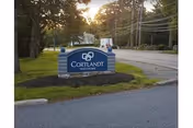 Blue Cortlandt Healthcare sign on a grassy roadside median.