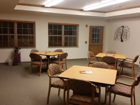 Interior dining room in a senior living facility with several tables and chairs.