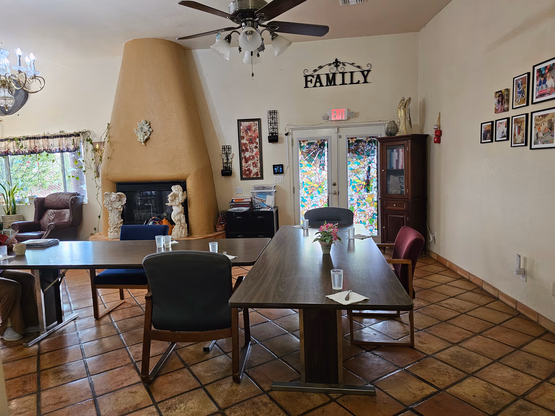 Interior dining area at Casa De Angeles with large table, chairs, fireplace, and photos on wall.