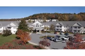 Harvest Hill senior living campus with white buildings, circular drive, and autumn-colored trees.