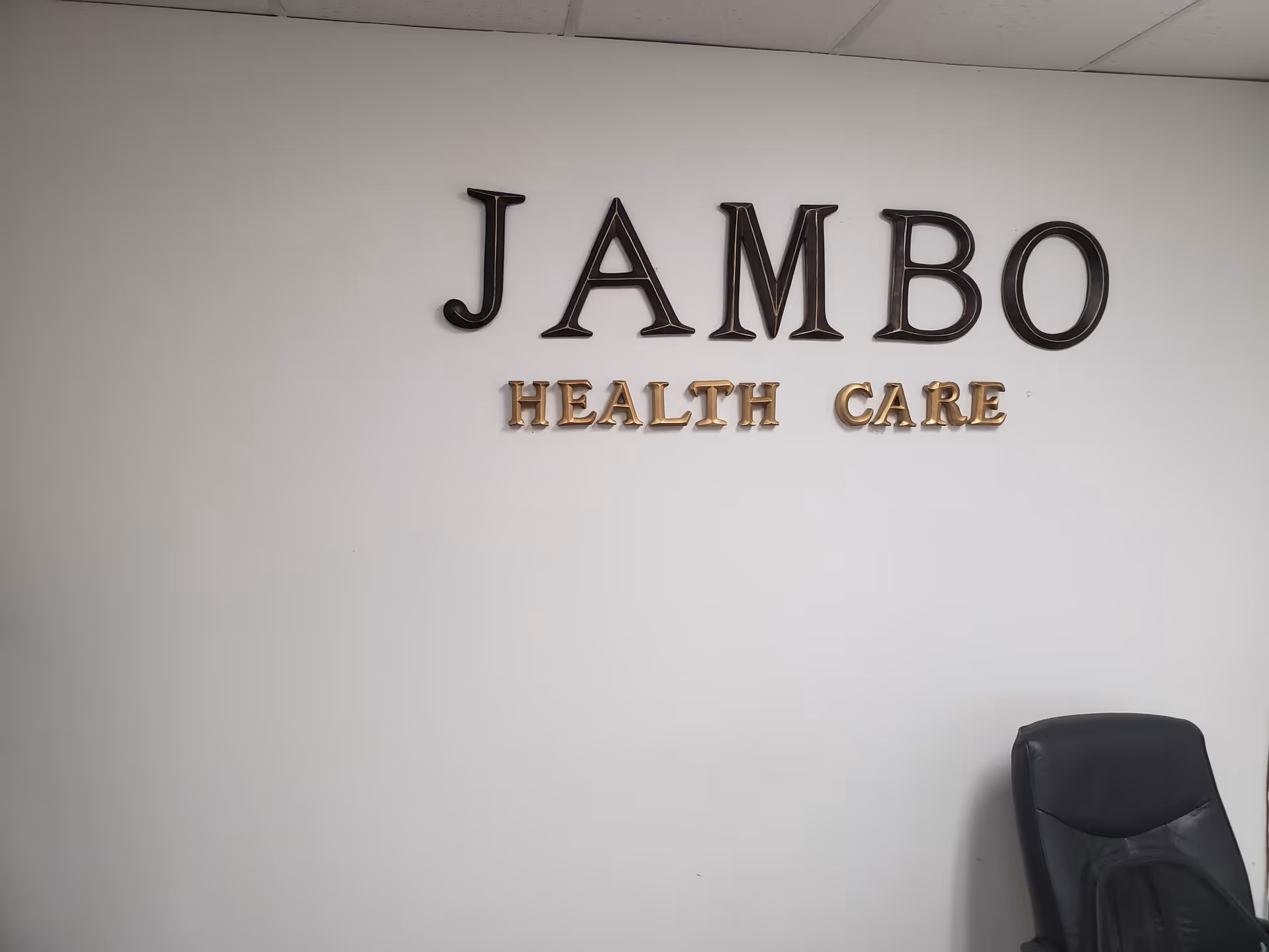 Indoor wall featuring JAMBO HEALTH CARE signage and a black office chair