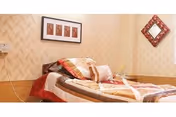 A cozy bedroom with a patterned quilt, pillows, and wall art.
