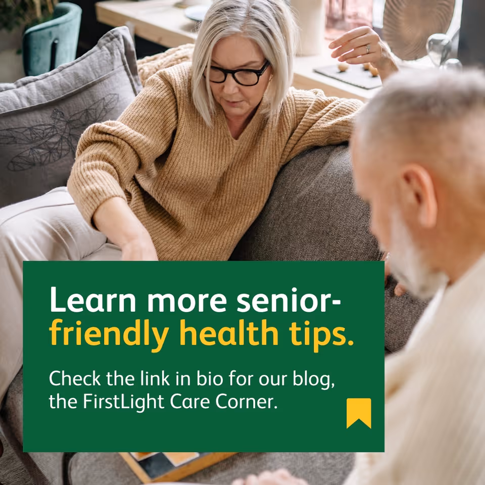 Two people sit on a couch in a cozy living room with a green banner.
