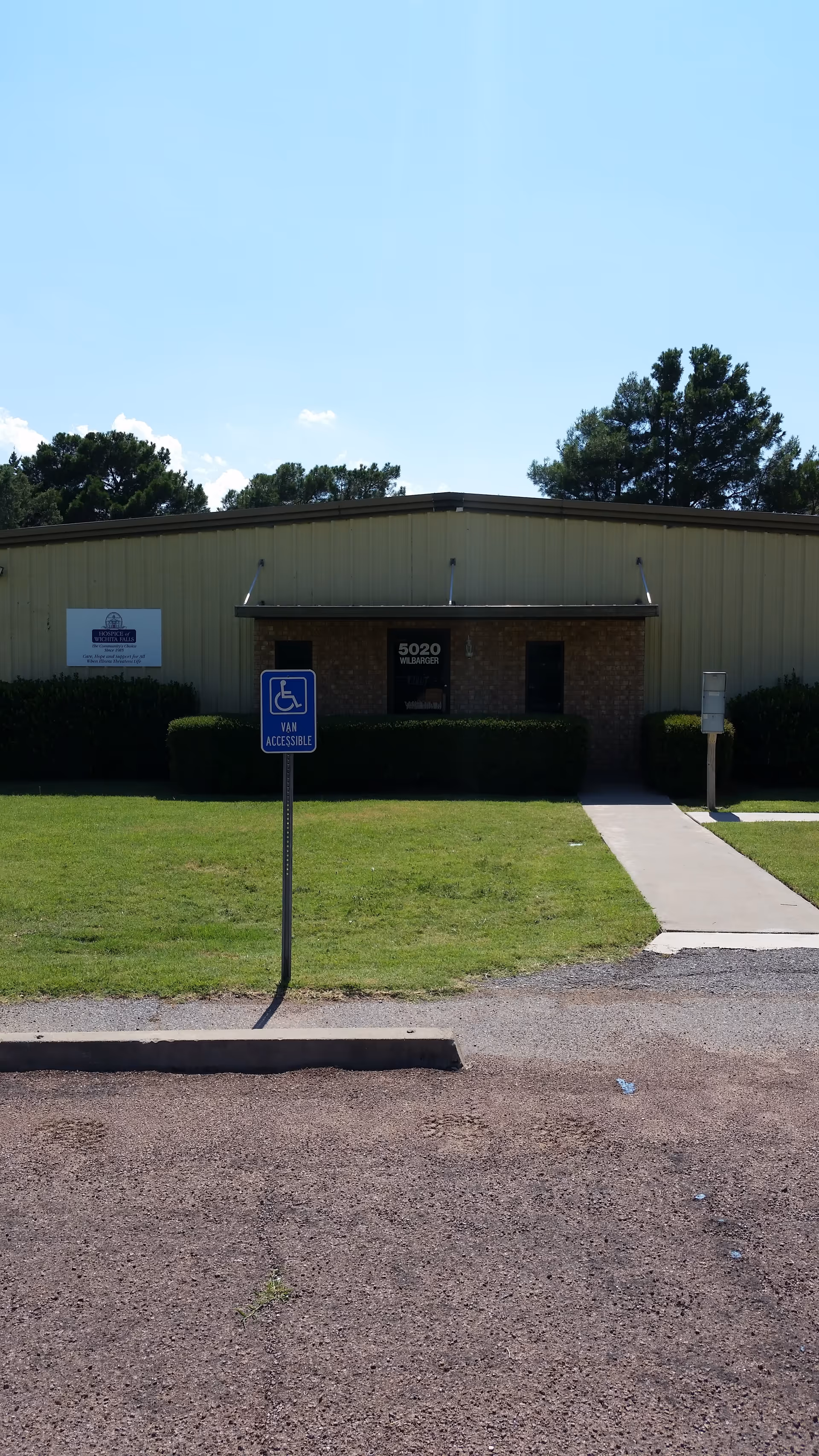 Exterior view of a single-story office building with a blue accessible parking sign and walkway.