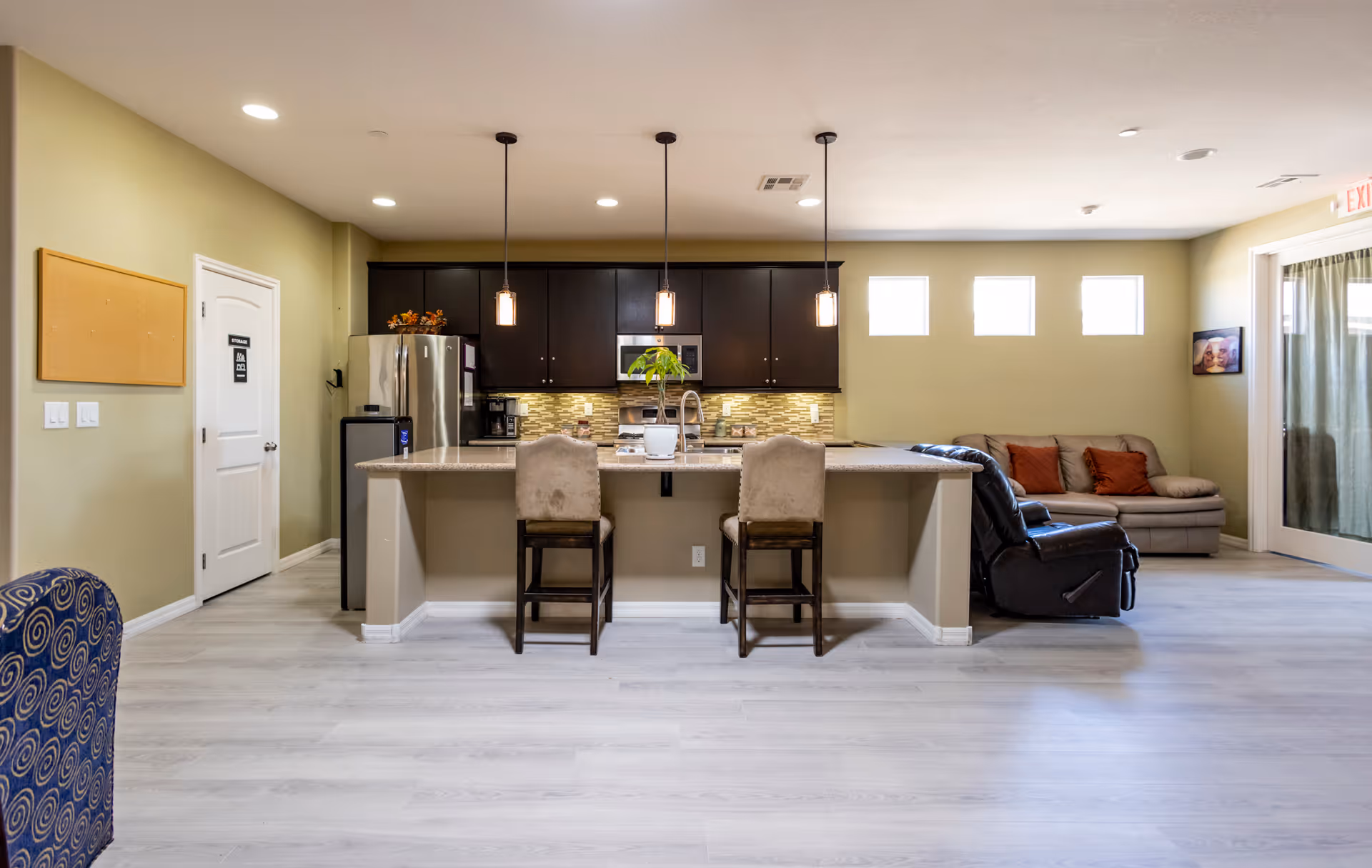 Open concept interior with a kitchen island, pendant lights, bar stools, and a sofa seating area.