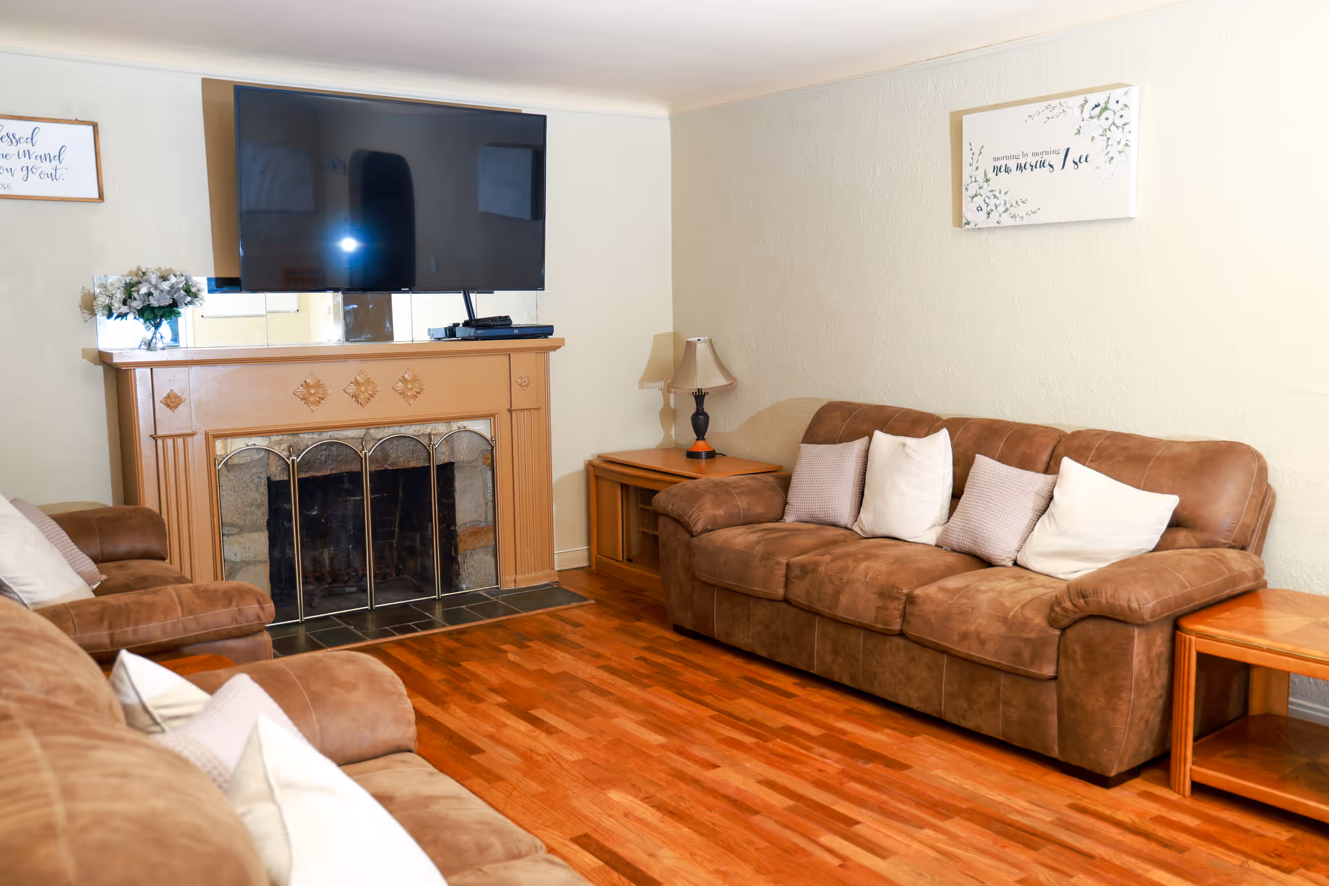 Cozy living room with brown leather sofas, a fireplace mantle, and a mounted TV.