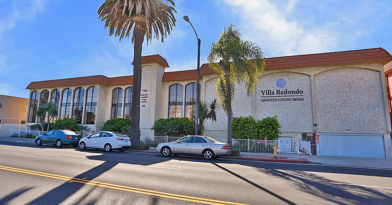 Exterior view of Villa Redondo Assisted Living Home with parked cars along the street.
