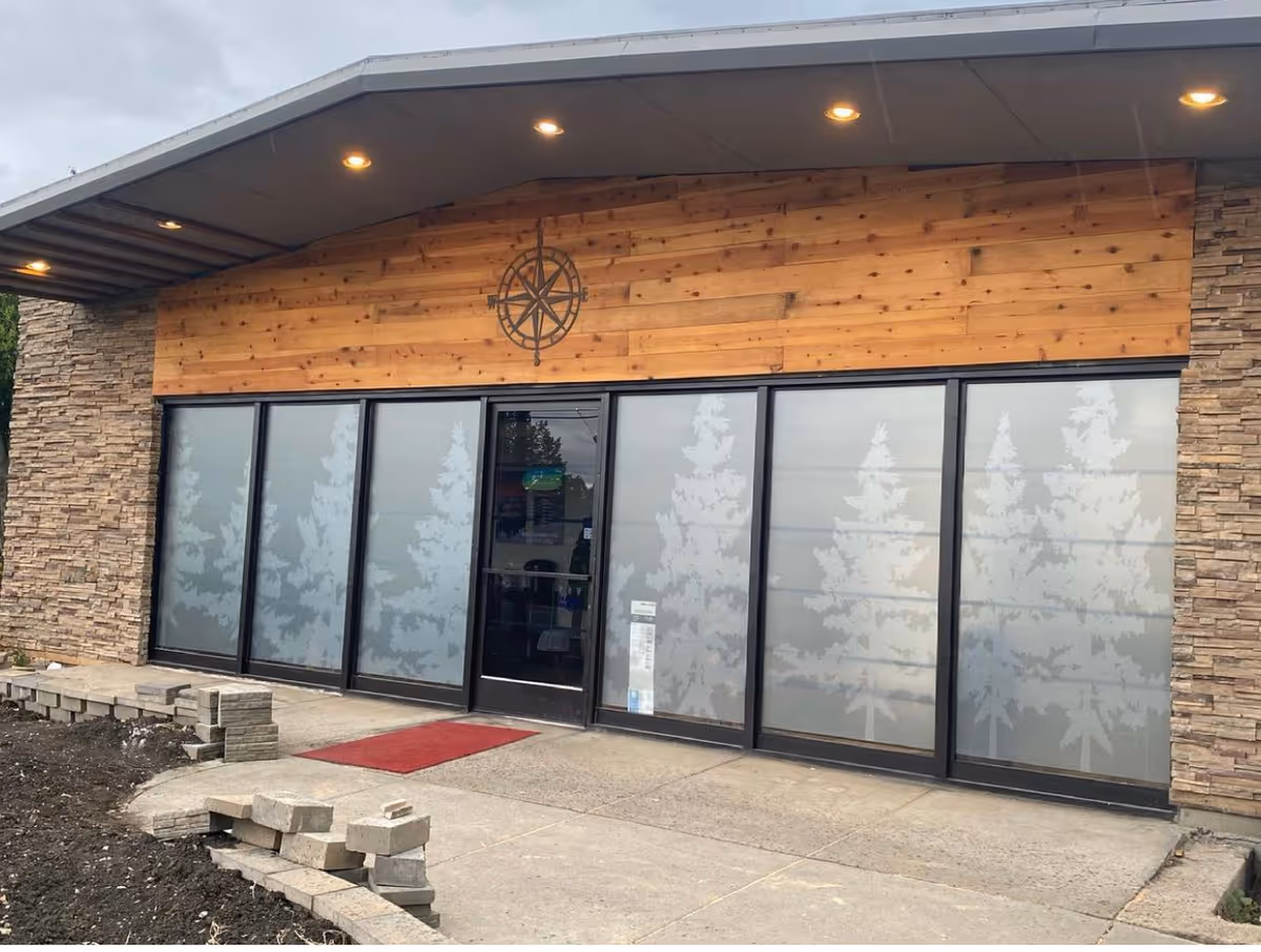 Front exterior of Rogue Valley Home Care Inc. building with glass doors and wood siding.