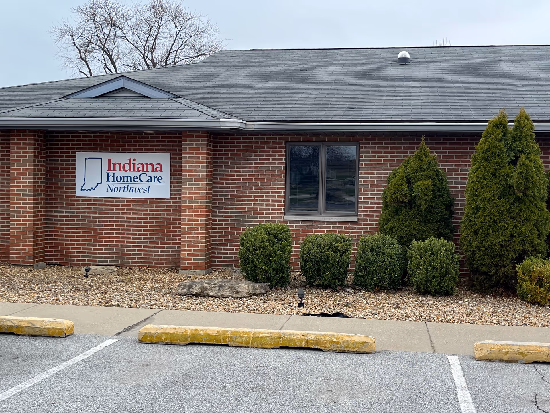 Brick exterior of a senior care facility with Indiana HomeCare Northwest sign and shrubs