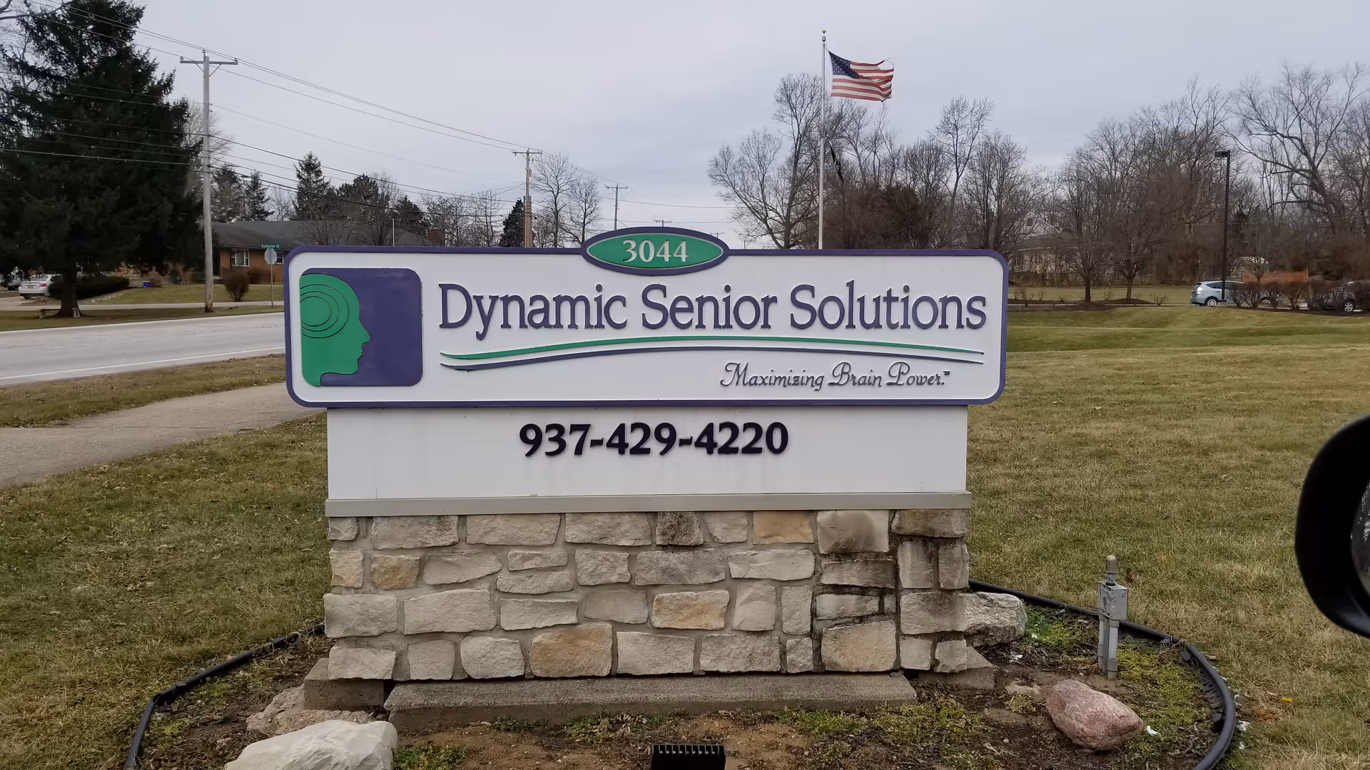 Outdoor sign for Dynamic Senior Solutions mounted on a stone pedestal with phone number