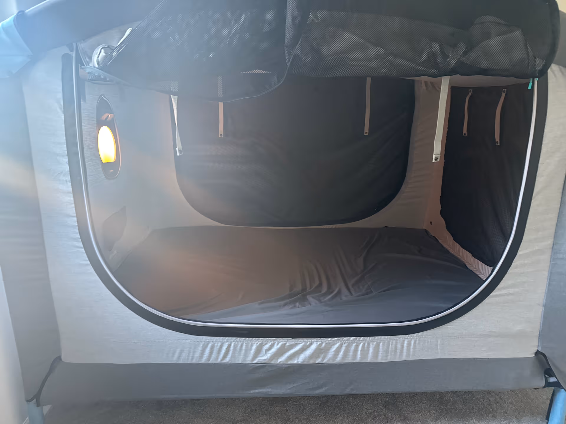 Interior view of a pod-style sleeping berth with dark bedding and zippered curtains.