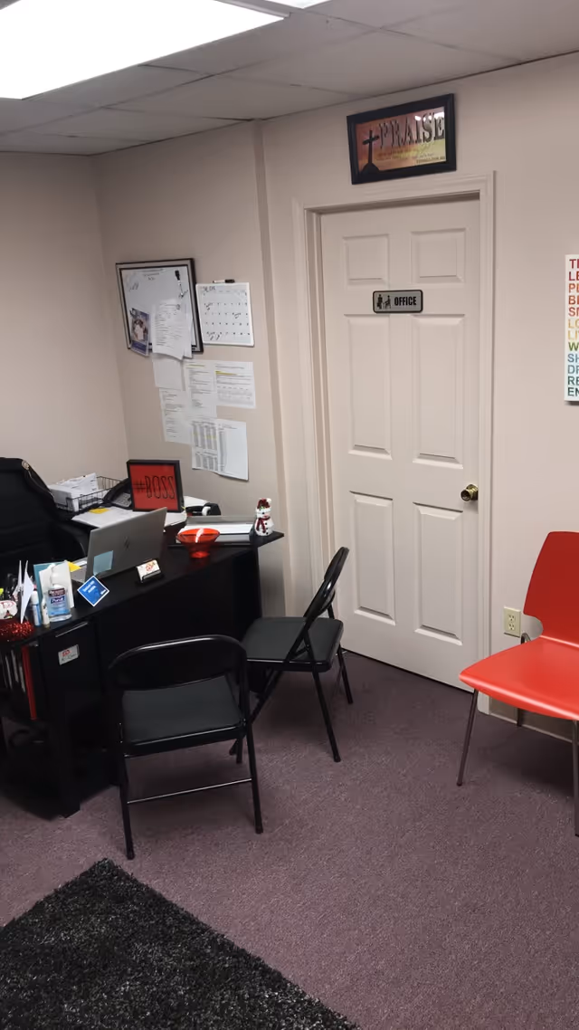 Interior office/reception area with desk, chairs, door labeled Office, and bulletin boards.