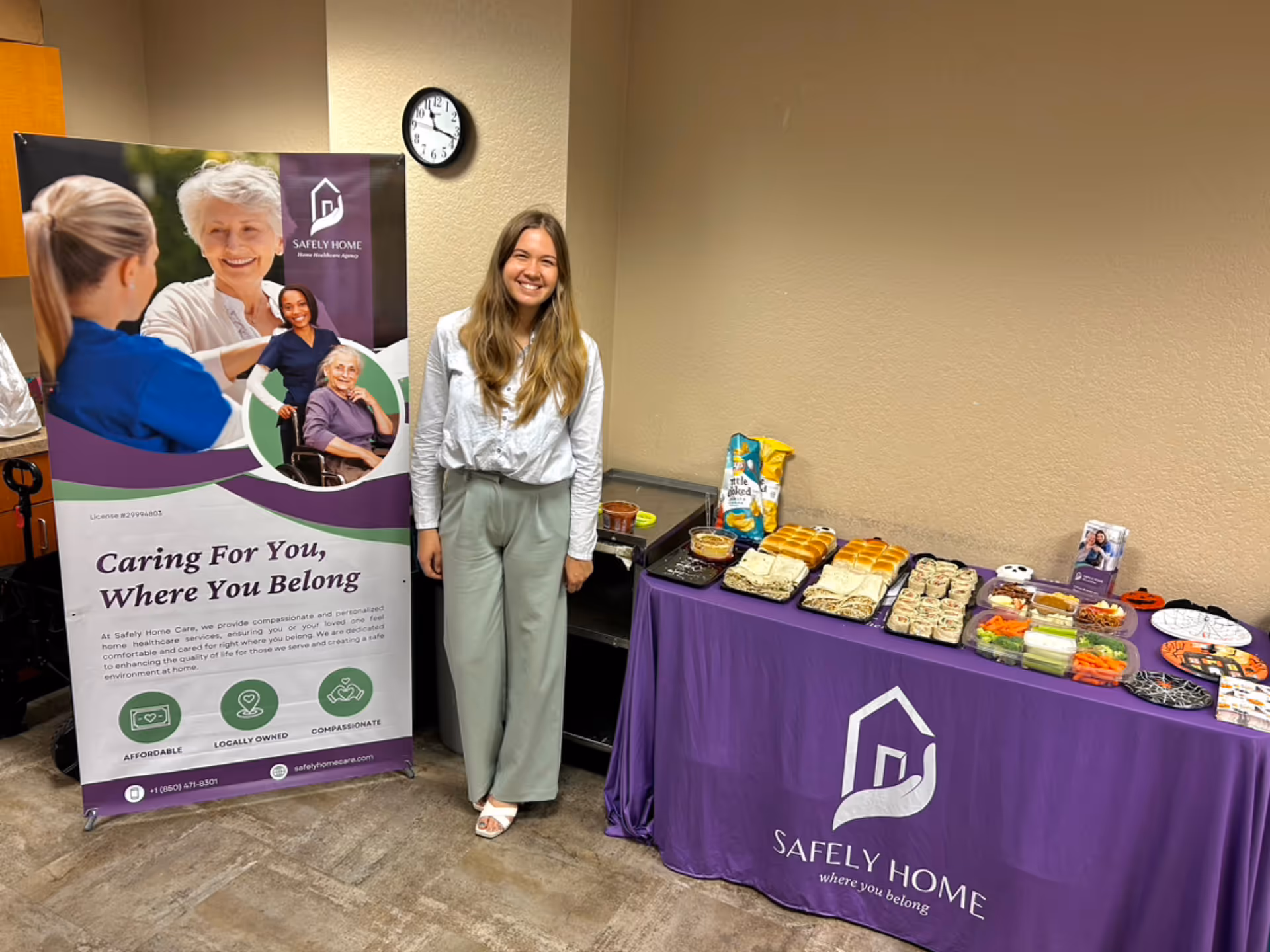 An interior room with a Safely Home Care banner and a long food table.