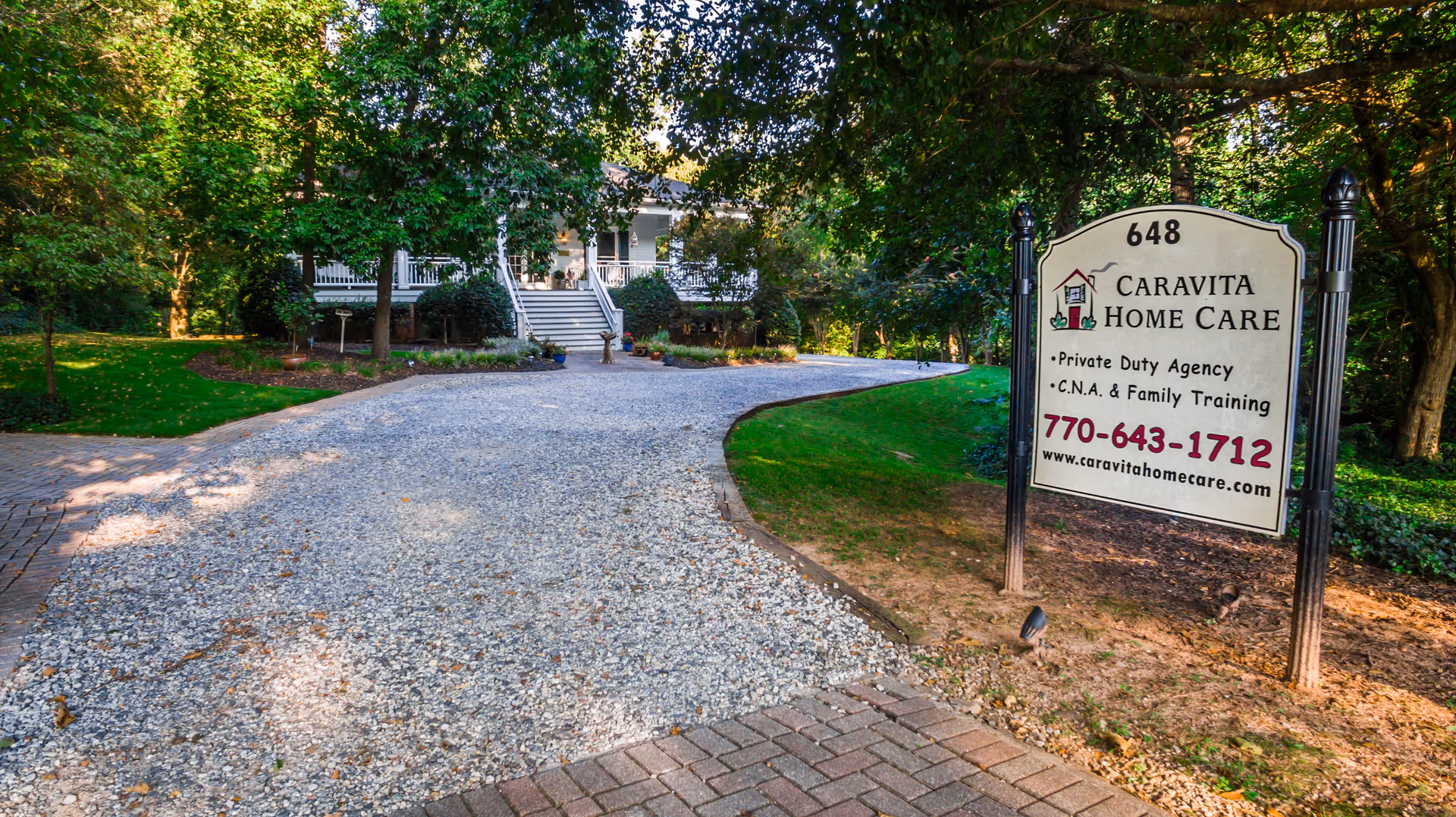 Gravel driveway leads to a house; CaraVita Home Care sign stands among trees.