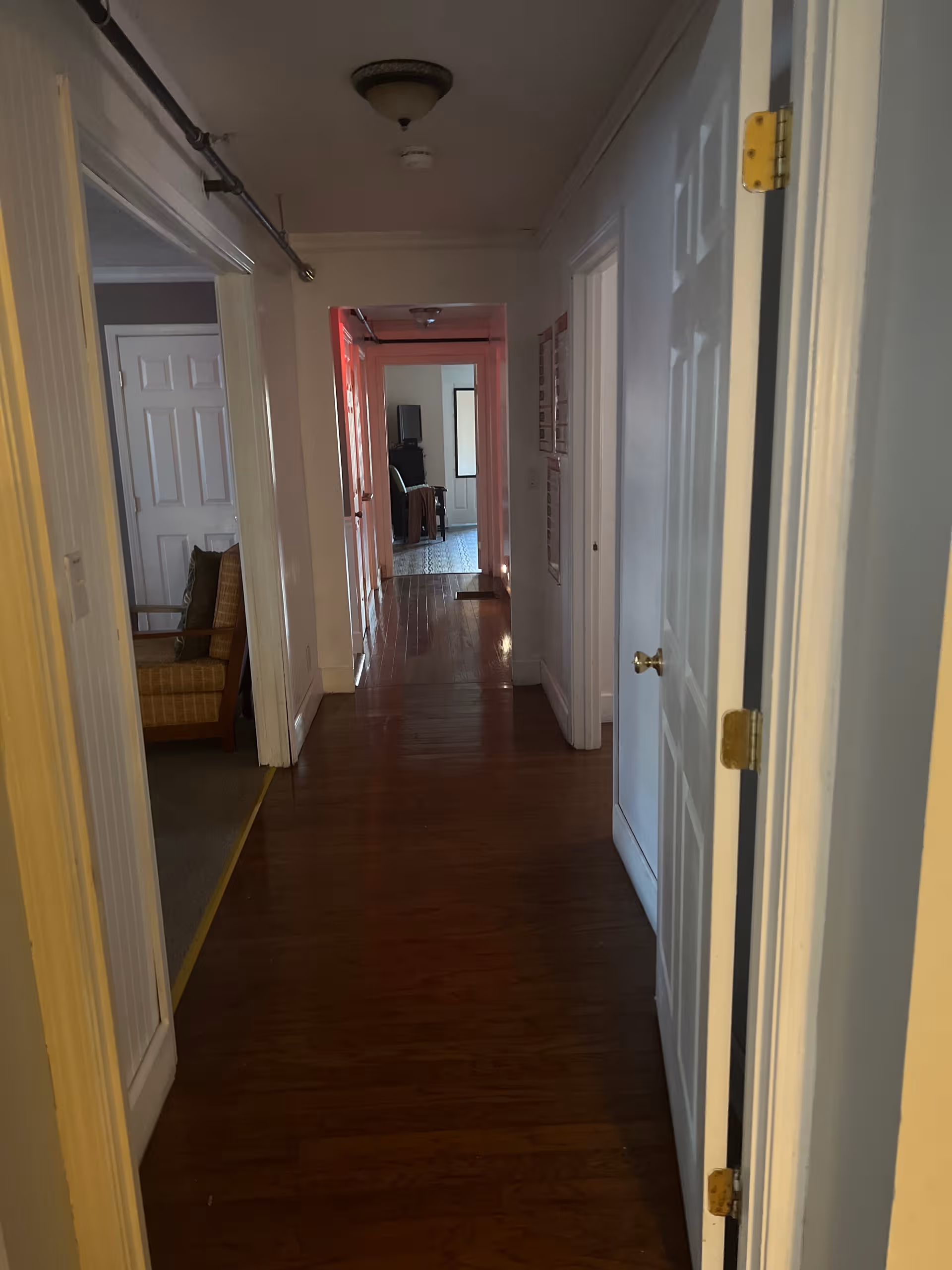 Narrow hallway inside a senior care facility with closed doors and wooden flooring.