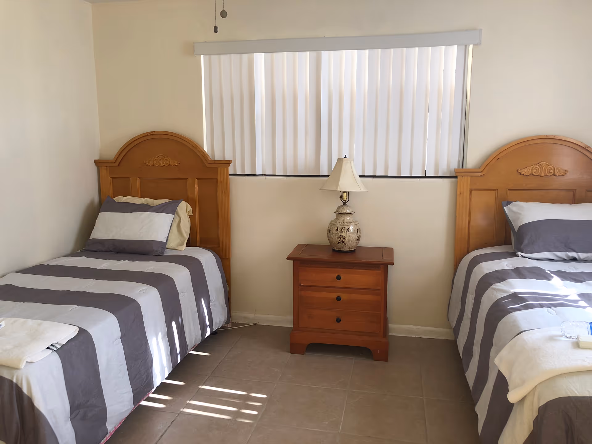 Two twin beds with wooden headboards, a nightstand, and a lamp between them.