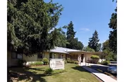 Front view of a single-story senior living facility with a sign and entrance walkway.