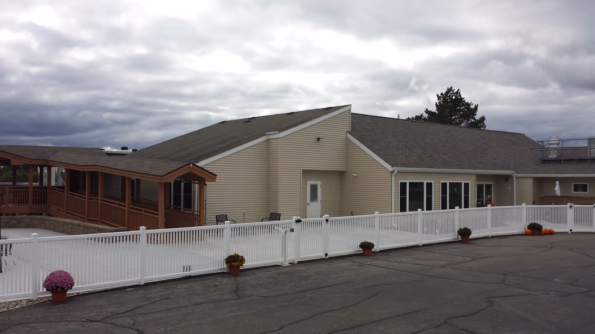 Exterior view of Pennfield Premier Living North with beige building, white fence, and deck.
